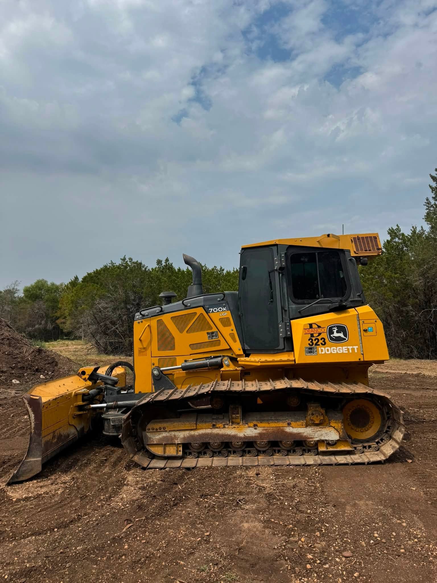 John Deere 700K dozer pushing brush on a cleared lot
